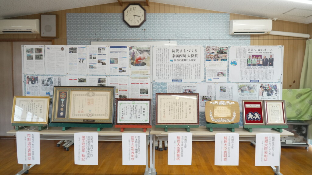 西崎ニュータウン自治会集会所に並べられた表彰状・賞状・新聞記事の全景