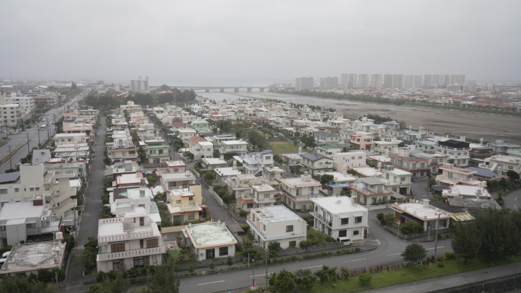 潮平高層住宅から見下ろした西崎ニュータウンの街並み。低層住宅が広がり、奥に海と橋が見える