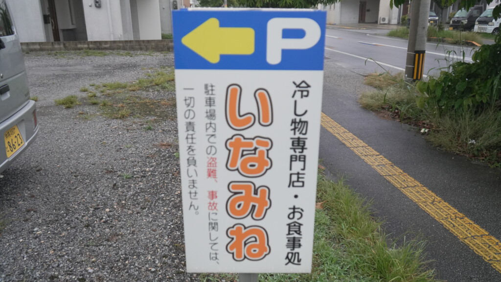 いなみね冷やしもの店の専用駐車場を示す立て看板。『P』のマークと矢印が描かれている