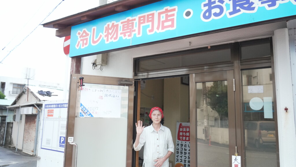 いなみね冷やしもの店の前で笑顔を見せる、店主の稲嶺さん