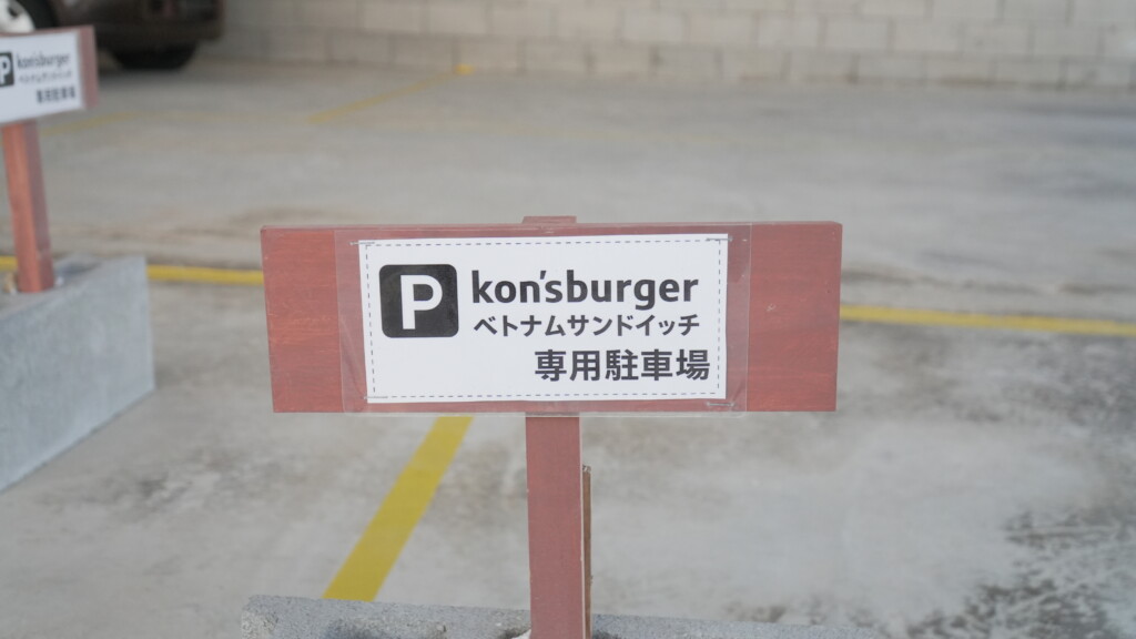 kon's burger ベトナムサンドイッチ 専用駐車場と書かれた看板。背景に黄色い線で区切られた駐車スペースが見える