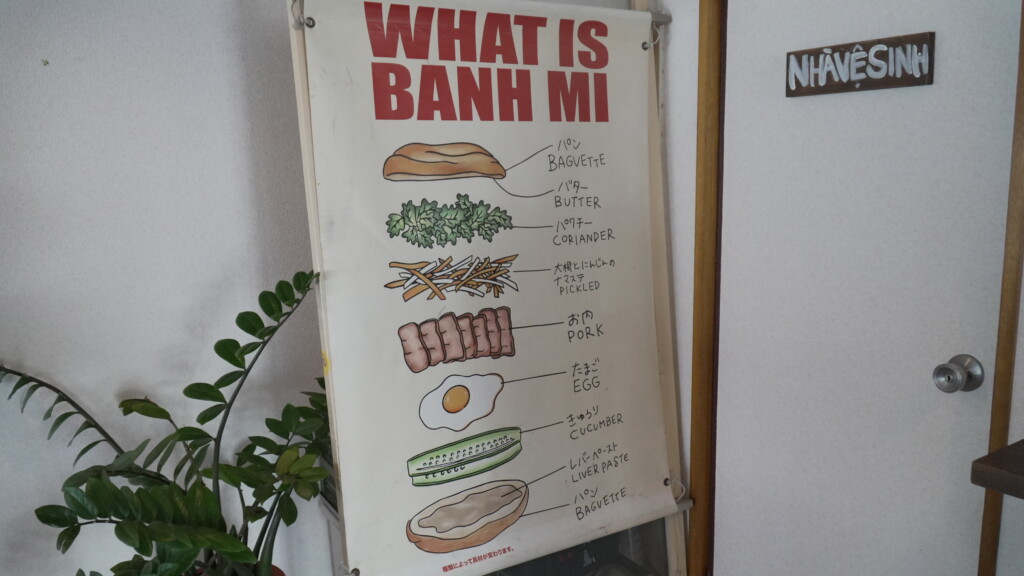 店内に掲示された『WHAT IS BANH MI』のイラストポスター。バゲット、バター、パクチー、ピクルス、ポーク、卵、きゅうり、レバーペーストの構成が図解されている